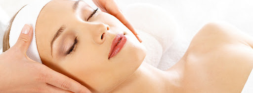 dłonie kobiece masują twarz młodej kobiety z zamkniętymi oczami i białą opaską na głowie