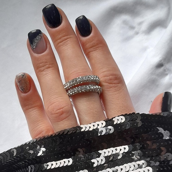 dłoń z wykonanym manicure żelem w różnych kolorach z pierścionkiem na palcu środkowym